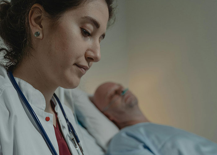 Female doctor with a stethoscope examining a male patient in a hospital room, revealing medical secrets and concerns.
