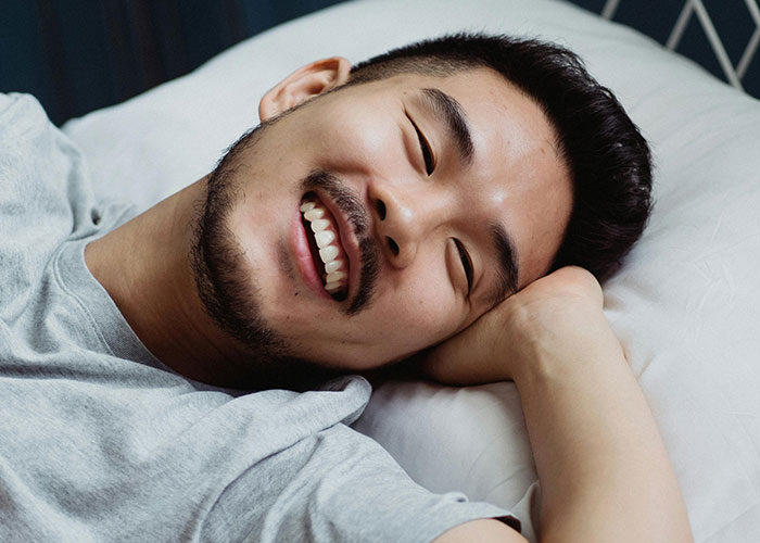 Jovem sorridente deitado na cama, refletindo felicidade e alívio, ilustrando o momento da revelação do divórcio.