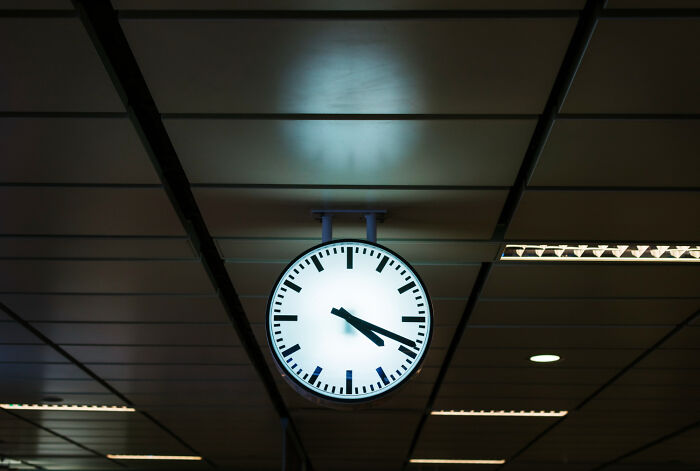 Glowing clock hanging from ceiling in a dimly lit room, evoking a spine-chilling haunted place atmosphere.