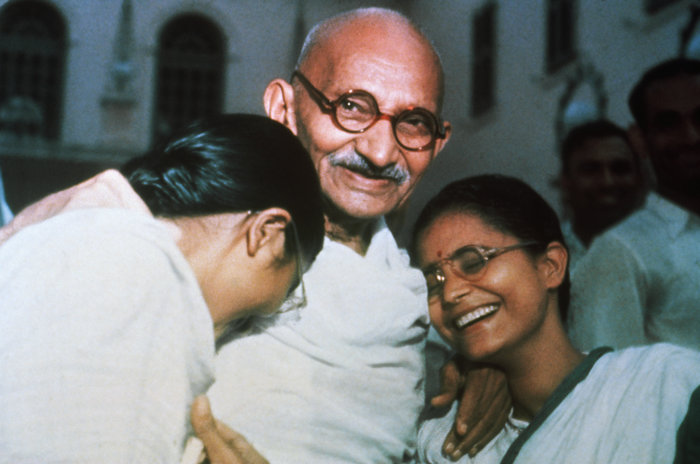 Gandhi smiling warmly with two women, representing famous leaders who changed history and inspired many.