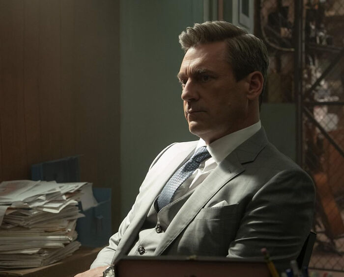 Man in a gray suit sitting at a desk with papers, reflecting the theme of celebrities people used to like but now hate.