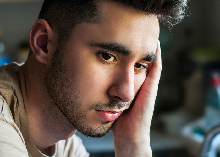 Young man looking thoughtful and sad, reflecting on the messiest love triangle and chaotic relationship secrets.