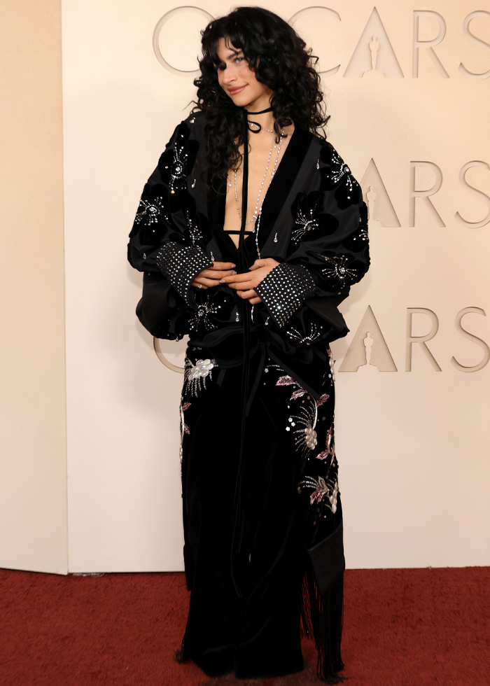 Person posing on red carpet wearing a black embellished outfit, one of the jaw-dropping outfits from Oscars 2026 fans loved.