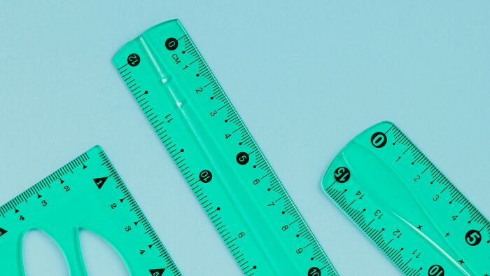 Three different green rulers arranged on a blue surface representing childhood memories and activities.