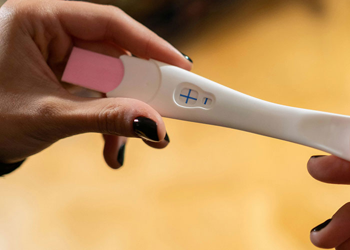 Two hands holding a positive pregnancy test, symbolizing messy love triangle secrets and chaotic relationship dynamics.