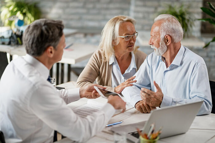 A mature couple discussing tough reasons for staying in a relationship with a professional in a modern office setting.