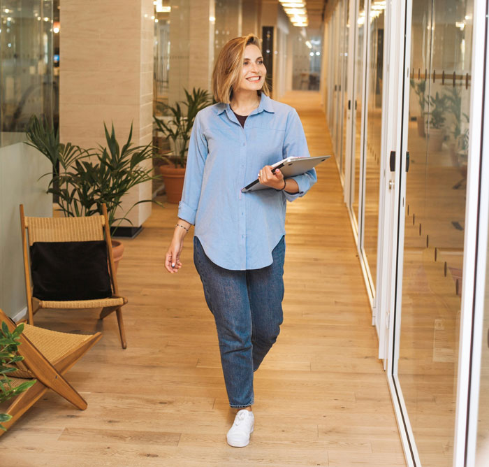 Mulher andando no corredor do escritório segurando um tablet, relacionado ao teste secreto de paternidade e ao cenário do bebê recém-nascido. Mulher andando no corredor do escritório segurando um tablet, relacionado ao teste secreto de paternidade e ao cenário do bebê recém-nascido.