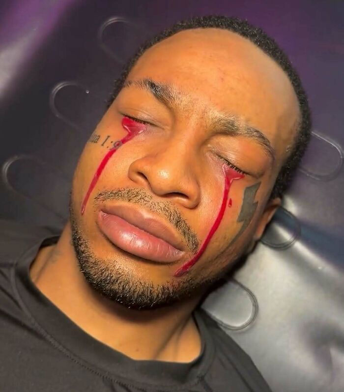 Close-up of a man with ink tattoo tears running from his eyes, illustrating ink fails and permanent regrets.