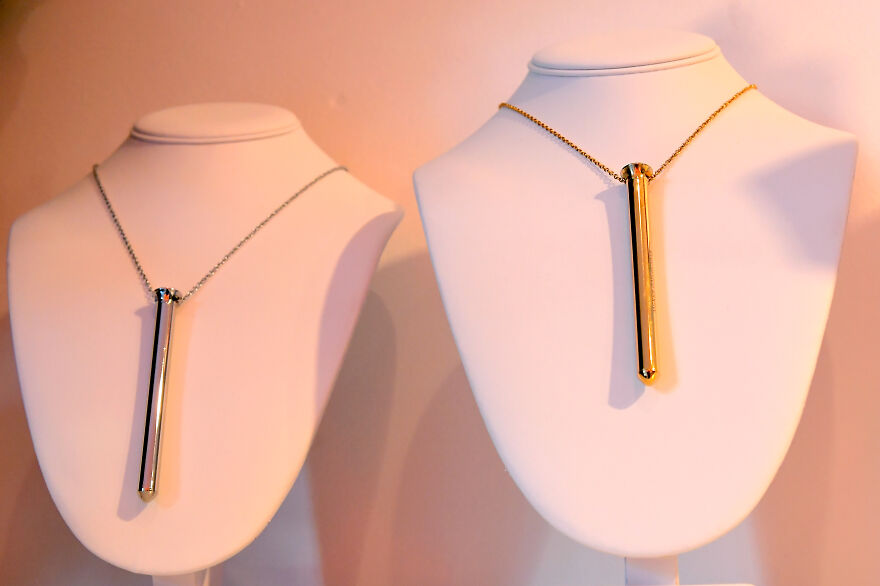 Two dazzling curious objects displayed as necklaces on white stands with a simple background in soft lighting.