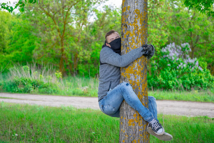 Young person wearing a mask hugging a tree outdoors, part of bizarre encounters in nature that leave folks questioning what they saw