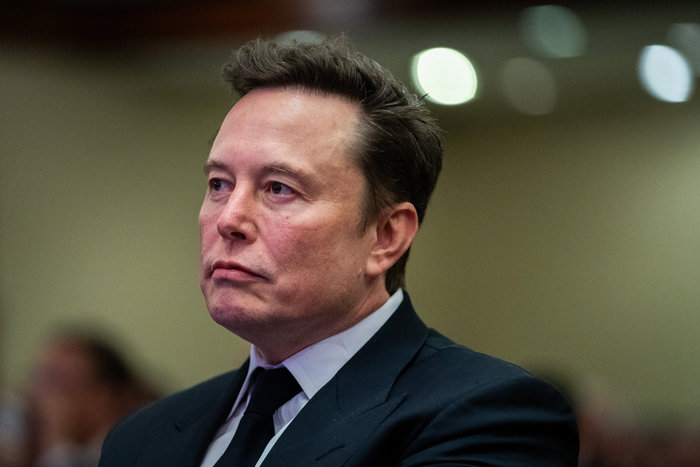 Elon Musk in a formal suit, attending an event, representing one of the famous leaders who changed history.
