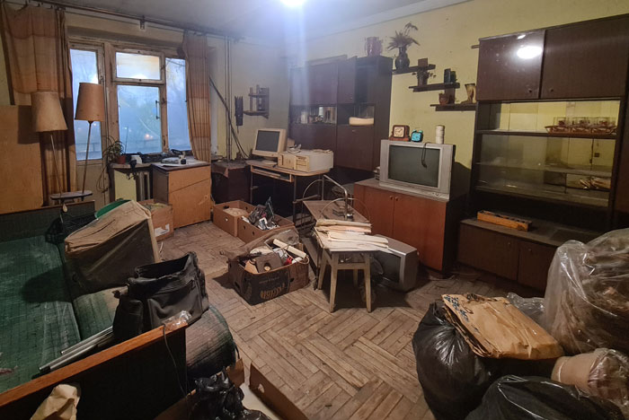 Sala desordenada cheia de móveis antigos e caixas, ilustrando o caos relacionado ao comportamento horrível do filho adotivo de uma mulher. Sala desordenada cheia de móveis antigos e caixas, ilustrando o caos relacionado ao comportamento horrível do filho adotivo de uma mulher.