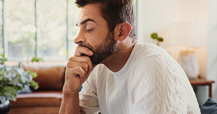 Single man in white sweater looks pensive at home after unexpected call from child services about legal father status. Single man in white sweater looks pensive at home after unexpected call from child services about legal father status.