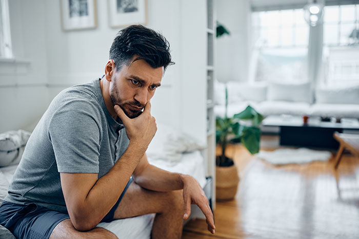 Man sitting alone looking sad and thoughtful, reflecting on hurt from family and strained nibling relationships.