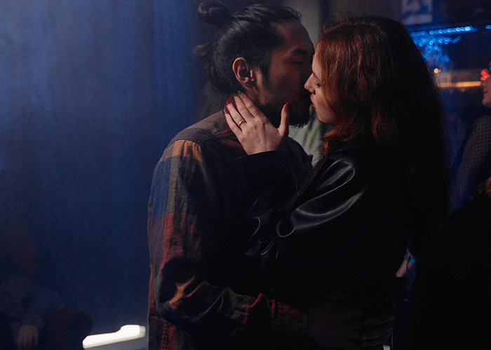 Couple sharing an intimate moment in a dimly lit room, highlighting a cheater hiding a one night stand secret.