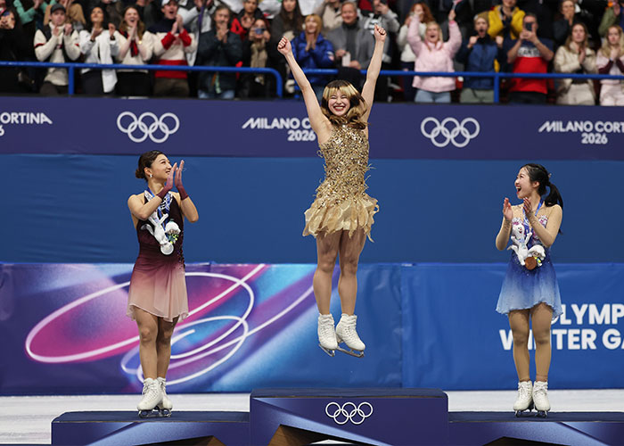Olympic hero Alysa Liu celebrating on the podium with fellow skaters during the Milano Cortina 2026 Winter Games.
