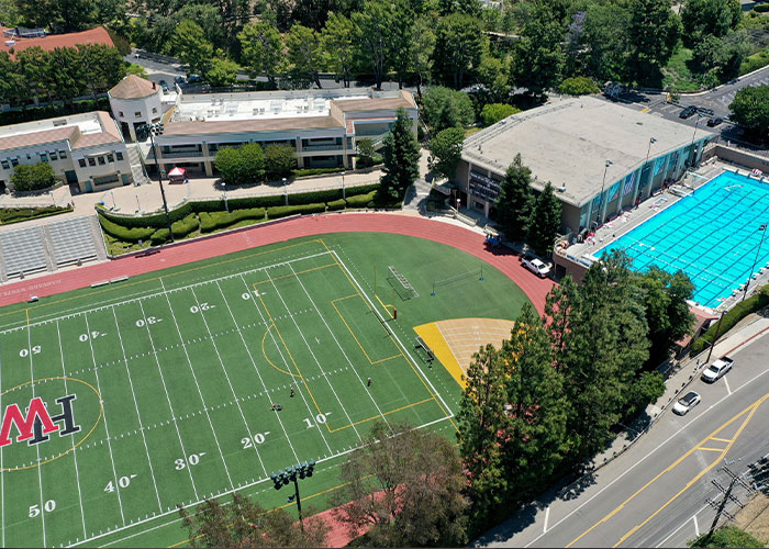 Aerial view of sports complex with football field and outdoor swimming pool linked to underwater incident with Hollywood connection.
