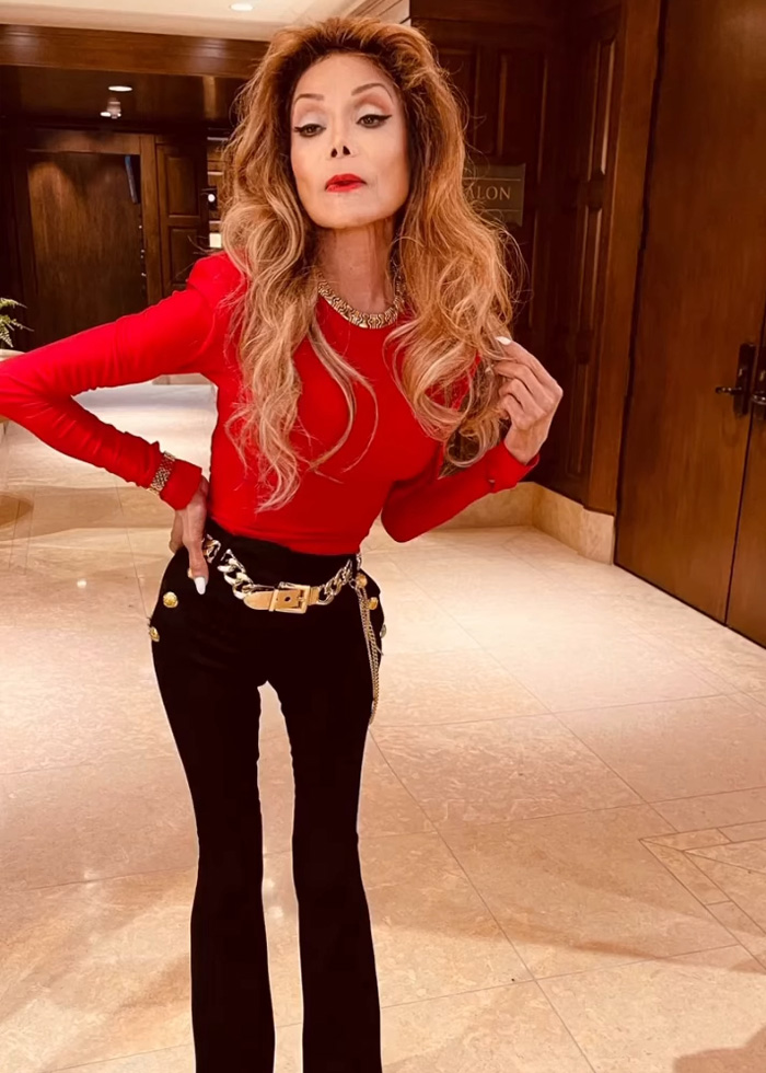 La Toya Jackson posing indoors in a red top and black pants, sparking concern among fans over her appearance.