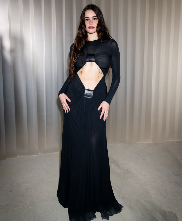Barbie Ferreira from Euphoria in a dramatic transformation wearing a black cut-out gown posing against a neutral backdrop.