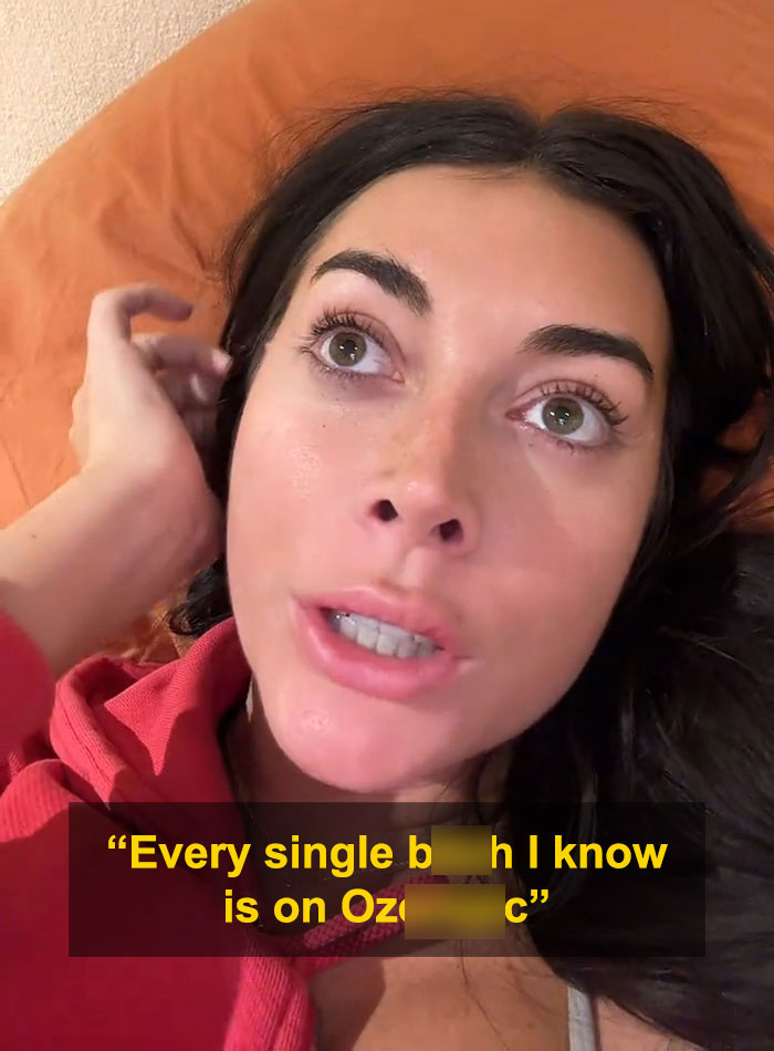 Woman speaking a harsh warning about weight loss injections while lying on an orange pillow wearing a red top.