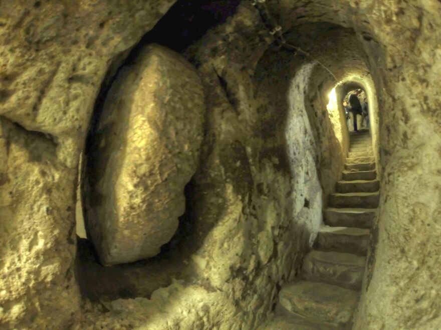 Narrow stone staircase inside an ancient underground city carved into rock, showing historical underground construction.