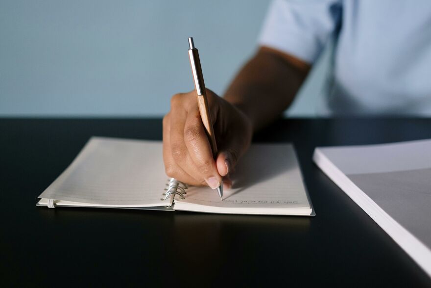 Person holding a pen and writing notes in a notebook applying practical psychology tricks for real-world situations.