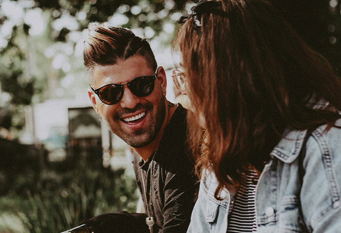 Woman trying to make longtime friend fall in love with her, smiling and talking outdoors during a casual moment together.