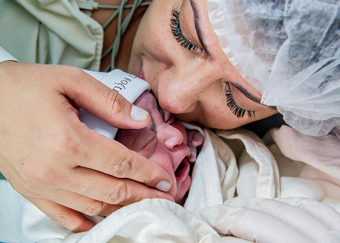 Newborn baby wrapped in a blanket cuddled closely by a woman, capturing a tender moment of love and care.