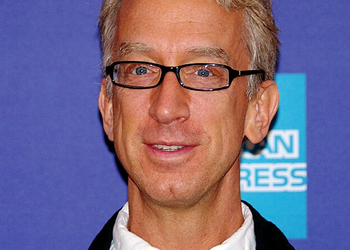 Man wearing black rectangular glasses and a suit jacket at an event about celebrities who turned out to be jerks.