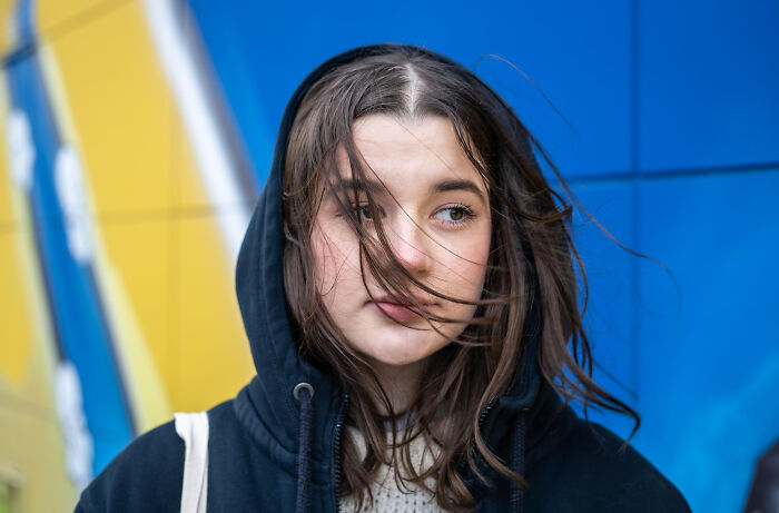 Young woman in a black hoodie with hair blowing, representing reactions to the Gen Z stare and 80s cultural comparisons.
