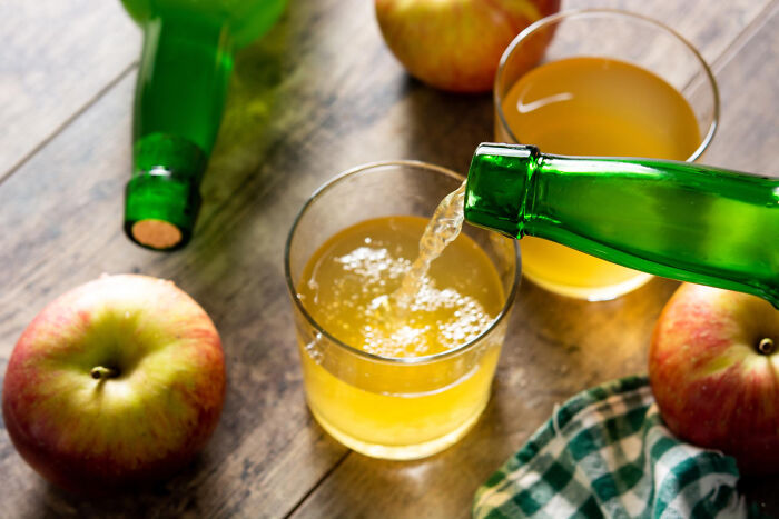 Pouring a premium-tier zombie drink into a glass surrounded by fresh apples on a wooden table.