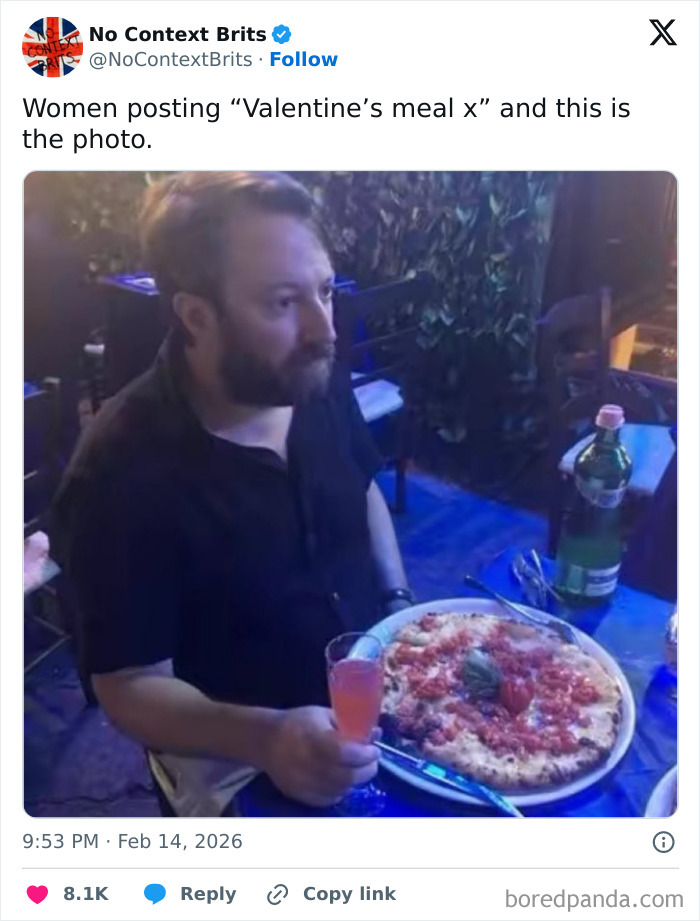 Man holding a drink and sitting at a table with a pizza, illustrating hilarious tweets about living in the UK experience.