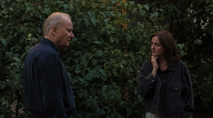 Two people having a serious conversation outdoors surrounded by greenery, reflecting 2026 Oscar predictions community trends.