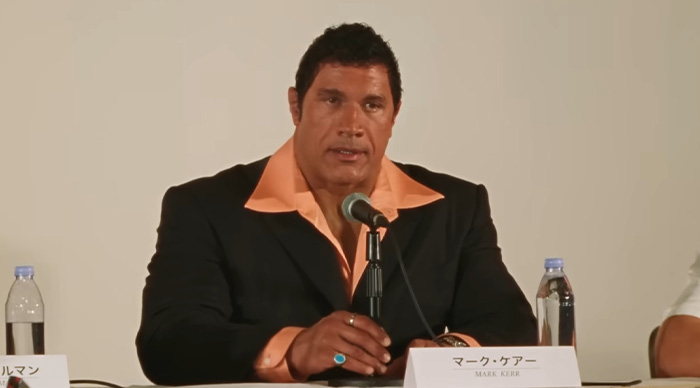 Man in a black suit with orange shirt speaking at a panel, related to 2026 Oscar predictions and community trends.