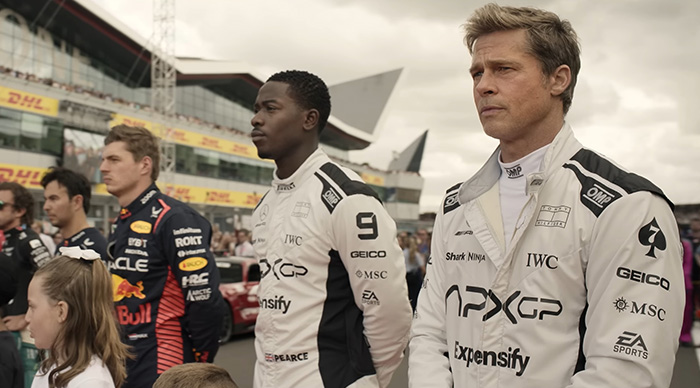 Actors in racing suits standing on a race track, a scene from a film related to 2026 Oscar predictions.