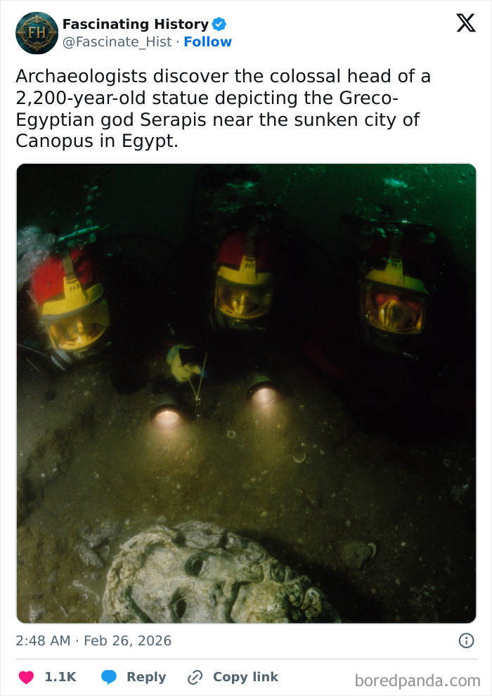 Underwater archaeologists with flashlights examine a colossal 2,200-year-old historical treasure statue head in Egypt.