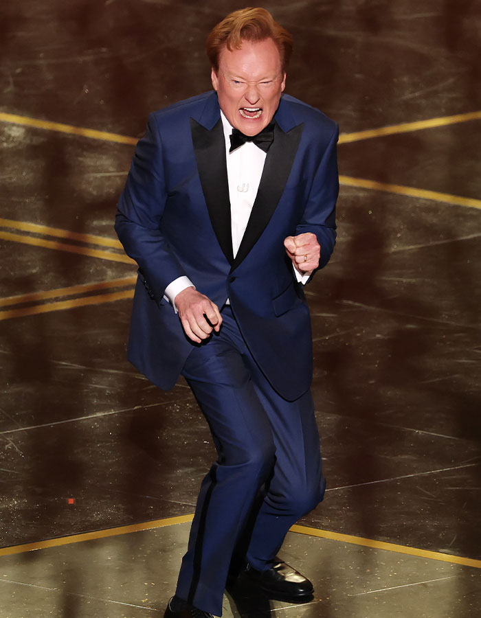 Conan O’Brien performing an energetic monologue during the Oscars 2026, sparking backlash over an awkward b*m drum joke. Conan O’Brien performing an energetic monologue during the Oscars 2026, sparking backlash over an awkward b*m drum joke.