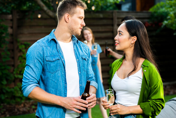 A man and woman holding drinks and talking outdoors, illustrating common misconceptions about being a woman.