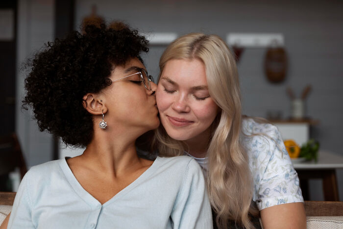 Two women showing affection in a cozy home setting, highlighting experiences women thought were part of being a woman.
