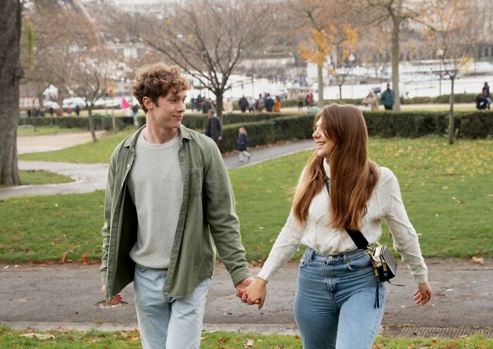 Young couple holding hands and smiling outdoors, illustrating common misconceptions about being a woman.