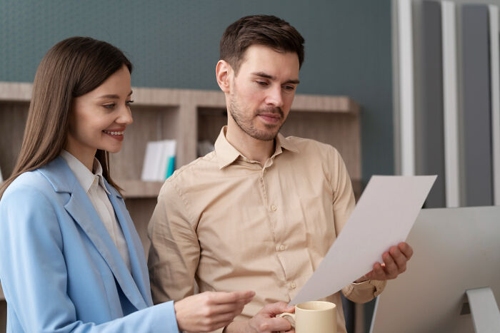 Two colleagues reviewing a document together in an office, illustrating moments people tried sabotage but faced karma.