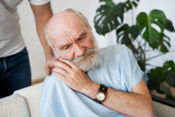 Elderly man receiving comforting support with a gentle touch, highlighting emotional care and connection.