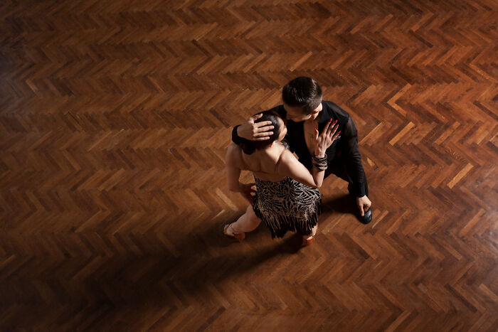 Couple dancing closely on dark wooden floor, capturing spine-chilling experiences in haunted places atmosphere.