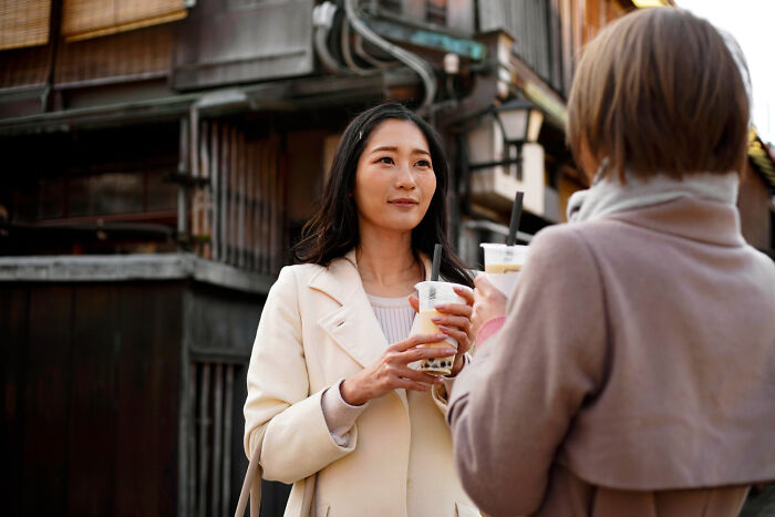 Two women enjoying bubble tea outdoors, highlighting cultural things people thought were normal until visiting other countries.