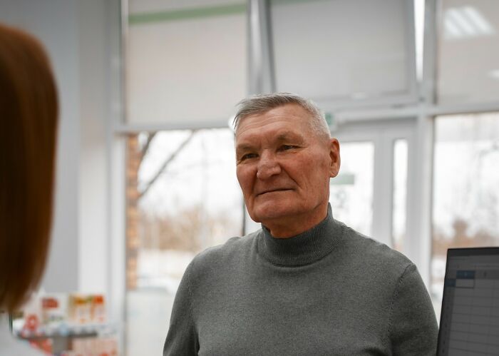 Older man in a gray turtleneck engaging in a conversation, illustrating reactions to Gen Z stare trends.