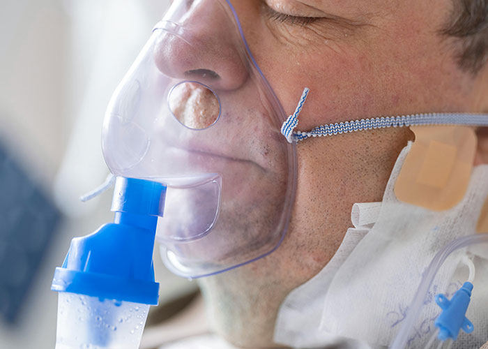 Close-up of a man wearing an oxygen mask showing a medical secret in a hospital setting.