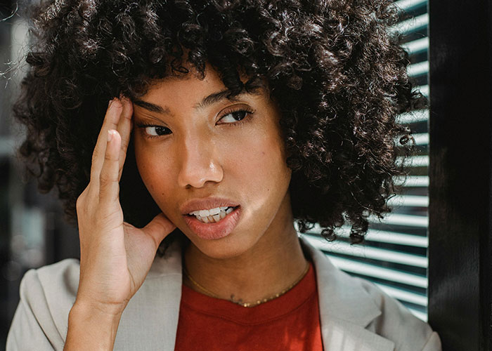Close-up of a woman with curly hair in thoughtful expression, reflecting on moments her ex revealed their true self.