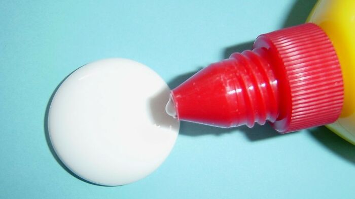 Close-up of white glue being squeezed from a red-tipped bottle, a nostalgic childhood activity many thought was unique.