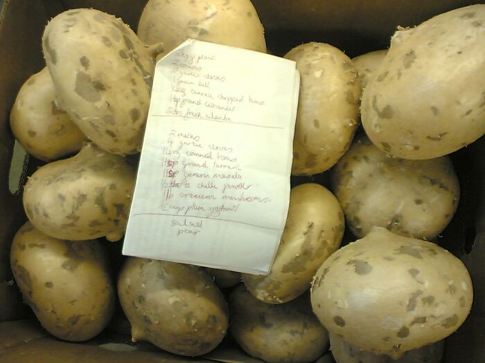 A handwritten note placed on a box filled with large, oddly shaped potatoes in a bizarre true story setting.