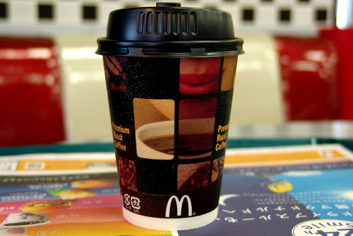 McDonald's coffee cup with black lid on a colorful table, highlighting disturbing images and facts about real life nightmares.